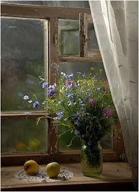 a vase filled with purple flowers next to two lemons and a window sill