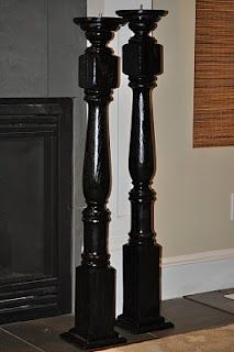 two black candlesticks in front of a fireplace