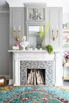 a living room with a fireplace, mirror and vases on the mantle in front of it