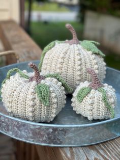 two knitted pumpkins sitting on top of a metal plate