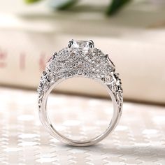 a diamond ring sitting on top of a table next to a book and flower bouquet