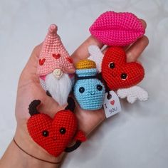 hand holding small crocheted items with hearts and gnomes on them for decoration