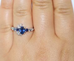 This Enchanting Ring features an oval shape 1.2 carat Blue Sapphire. Flanked by .30 carat 2 shiny deep blue sapphires, .20 carat aqua color 2 sapphires, .40 carat 7 Ice Gray Diamonds. Set in 14k white gold. Can be custom made in rose or yellow or white gold. Please choose the gold color at checkout. OOAK (one-of-a-kind) ring makes you the owner of something that nobody else has. Find your true style! Own this ring! Ethical Sourcing: This ring has a natural, ethically-sourced stones and recycled Oval Sapphire Promise Ring, Sapphire Promise Ring With Marquise Cut, Marquise Cut Sapphire Ring In Fine Jewelry Style, White Gold Sapphire Ring With Accent Stones For Proposal, Oval Sapphire Promise Ring With Ethical Diamonds, Oval Sapphire Diamond Ring With Multi-stone, Sapphire Marquise Promise Ring, Sapphire Diamond Ring With Accent Stones, Marquise Sapphire Ring In White Gold