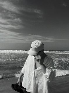 black and white photograph of a person on the beach holding a skateboard in his hand