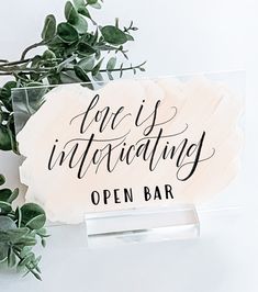 an open bar sign with greenery on the side next to it and a plant