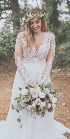 a woman in a wedding dress standing on a path with flowers and greenery around her head