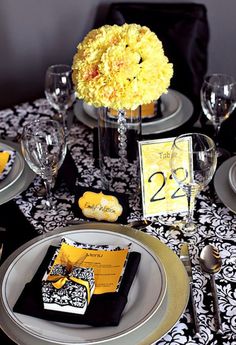 the table is set with yellow flowers and place settings for guests to sit down at