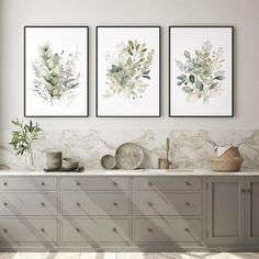 three framed paintings on the wall above a sink in a room with marble counter tops