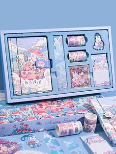 an assortment of stationery items is displayed on a blue tablecloth with unicorns