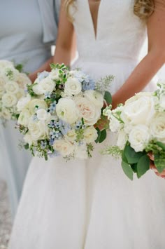 two bridesmaids holding bouquets of white and blue flowers in their hands,