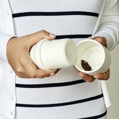 a woman is holding a cup with some food in it and has her hand on the coffee mug