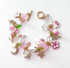 This delicate lily of the valley charm bracelet is handcrafted by myself.  The gold plated chain is 8 inches long with a toggle clasp.  It contains flowers, fairies, a glass butterfly, mushroom, hearts, moon, star and lots of crystals so it sparkles as you move.  If you need it shorter or longer just let me know, and I will adjust it to as close as possible to the size you desire.  Each charm is placed with thought  for color and balance.  It is  a really pretty bracelet, and sure to make you sm Bunny Cottagecore, Cottagecore Butterfly, Butterfly Mushroom, Beaded Ideas, Mushroom Jewelry, Fairy Jewelry, Glass Butterfly, Butterfly Bracelet, Star Moon