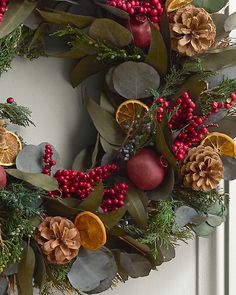 a wreath with oranges, berries and pine cones on the front door for christmas