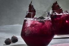 two glasses filled with liquid and some berries