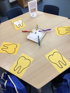 a wooden table topped with yellow cut out pieces of paper and toothbrushes on top of it