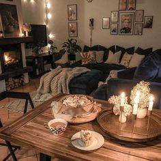 a living room filled with furniture and candles on top of a wooden table in front of a fire place