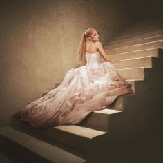 a woman in a white dress sitting on some stairs with her back to the camera