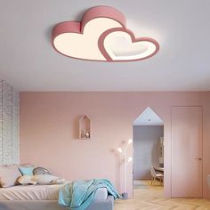 a bedroom with pink walls and wooden floors has a white cloud shaped light above the bed