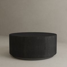 a black round table sitting on top of a white floor next to a gray wall