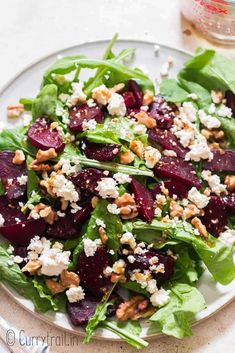 a salad with beets, feta cheese and walnuts on a white plate