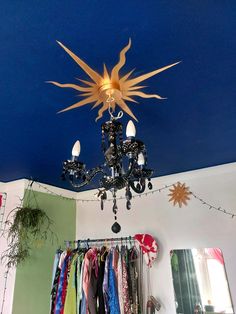 a chandelier hanging from the ceiling in a room with clothes on hangers