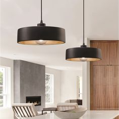 two lights hanging from the ceiling in a living room next to a table and chairs