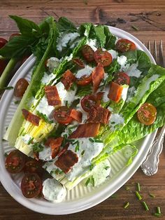 lettuce and tomato salad on a white plate with silverware next to it