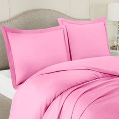 a bed with pink sheets and pillows on it