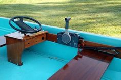 the inside of a boat with steering wheel and wooden table on it's side