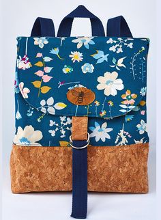 a blue backpack with flowers on it and a brown strap around the front pocket is shown