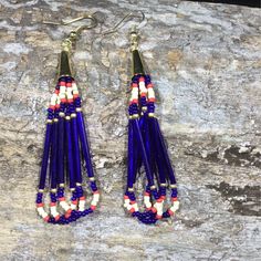 a pair of blue and white beaded earrings sitting on top of a stone slab