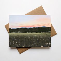 two greeting cards with an image of a field and mountains in the background at sunset