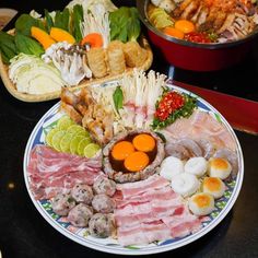 an assortment of meats and vegetables on a plate with other foods in the background