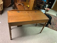 an old wooden table in a room with chairs and other items on the floor behind it