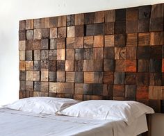 a bed with white sheets and pillows in front of a wall made out of wooden blocks