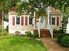 a small house with red shutters on the front door and steps leading up to it