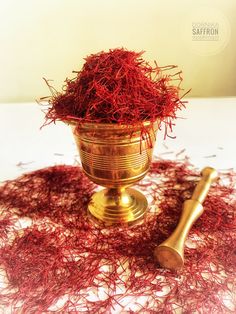 a golden bowl filled with saffron next to a wooden spoon on top of a table