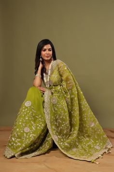 Look royal in this olive green organza saree with embroidery on festive occasions! It comes with a matching blouse piece. Disclaimer: The actual product may vary slightly from the image. These are custom orders, hence expect slight variation in color, placement of the motif or buta. ESTIMATED DELIVERYBecause this is a custom order, it would take about 4 weeks from the date of purchase. RETURN POLICYThis product is a custom order and cannot be returned or exchanged. Designer Green Organza Saree, Green Organza Traditional Wear With Traditional Drape, Traditional Green Organza Wear With Traditional Drape, Green Organza Pre-draped Saree With Cutdana, Green Chikankari Pre-draped Saree For Diwali, Green Organza Pre-draped Saree For Festivals, Green Chikankari Embroidery Sharara In Chanderi, Green Chanderi Sharara With Chikankari Embroidery, Green Chikankari Chanderi Sharara