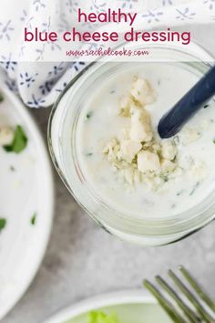 a glass jar filled with blue cheese dressing next to two plates of salad and silverware