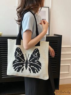 a woman carrying a black and white bag with a butterfly design on the front pocket