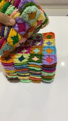 a stack of multicolored crocheted granny afghans sitting on top of a table