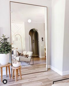 a living room filled with furniture and a large mirror on the wall above it's doorway