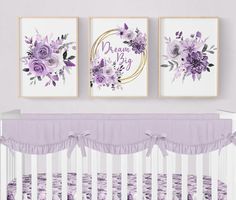 a baby crib with purple flowers on the wall and two framed pictures above it