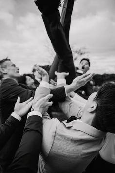 a group of people holding hands in the air with one person reaching up for something