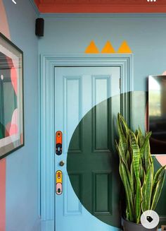 a house plant in front of a blue door with an oval design on the wall