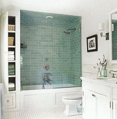 a bathroom with green tile and white fixtures, including a shower stall in the corner