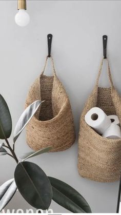 two baskets hanging on the wall with toilet paper in them