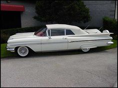 an old white car parked in front of a building