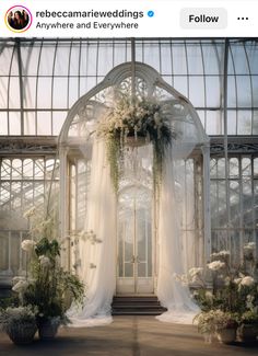 an outdoor wedding venue with white flowers and greenery on the front door, surrounded by large glass windows