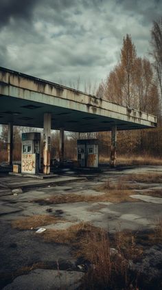 an abandoned gas station with graffiti on the roof and no people around it, under a cloudy sky